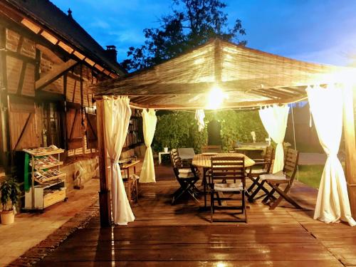 eine Holzterrasse mit einem Tisch und weißen Vorhängen in der Unterkunft Retour à la nature et au calme ! in Bosjean