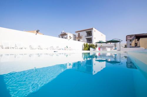 uma piscina com água azul e edifícios brancos em Villa Concettina em Capo dʼOrlando
