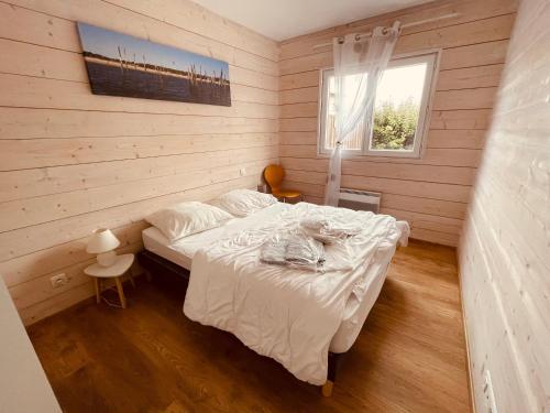 a bedroom with a bed in a wooden room at Maison Bois du Bassin in Andernos-les-Bains