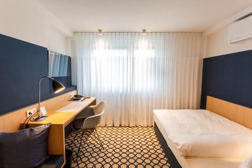 ビーティッヒハイム・ビッシンゲンにあるホテル オッターバッハのベッドとデスクが備わるホテルルームです。