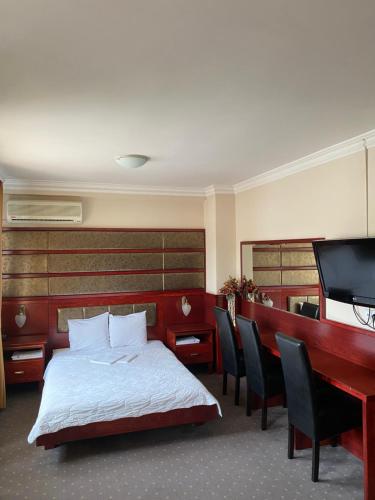 a bedroom with a bed and a desk and a television at Hotel Kamel in Banja Luka