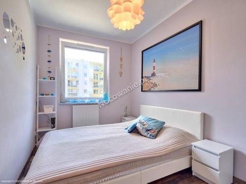 a bedroom with a bed with a large picture on the wall at Leśne Tarasy apartament Krabik Dziwnówek in Dziwnówek