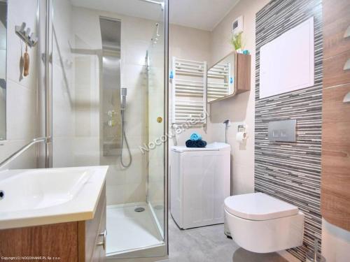 a bathroom with a toilet and a sink and a shower at Leśne Tarasy apartament Krabik Dziwnówek in Dziwnówek