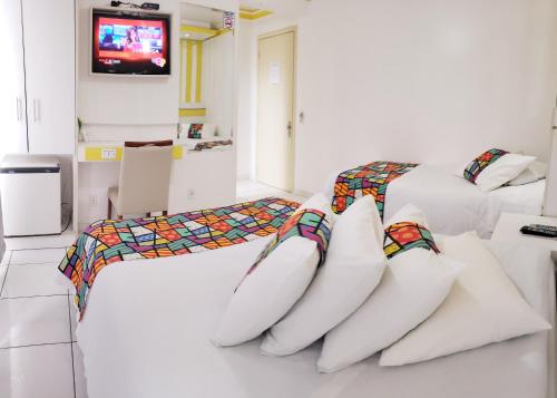 two beds with pillows in a room with a tv at Capão da Canoa - Hotel Rediadri in Capão da Canoa