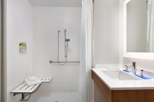 uma casa de banho branca com um lavatório e um chuveiro em Holiday Inn Express Hotel & Suites Merced, an IHG Hotel em Merced