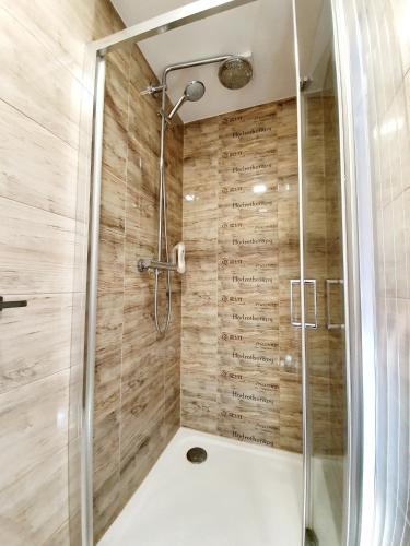 a bathroom with a shower with wooden walls at Wellness Apartmány EMPORIO in Loštice