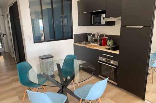 een keuken met een glazen tafel en blauwe stoelen bij Vue mer port de garavan in Menton