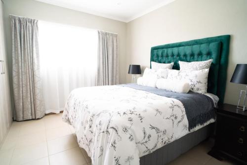 a bedroom with a large bed with a green headboard at Lalata House in Northwold