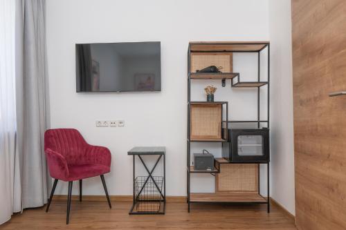 a living room with a red chair and shelves at Hotel Dortmunder Hof in Würzburg