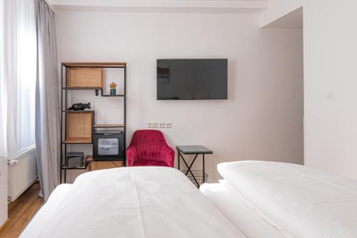 a bedroom with two beds and a tv on the wall at Hotel Dortmunder Hof in Würzburg