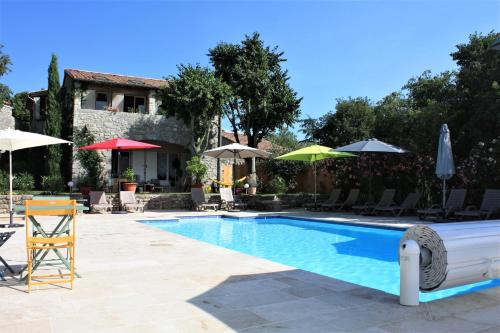 uma piscina com cadeiras e guarda-sóis e uma casa em Gîtes Domaine de la Barnerie em Saint Alban Auriolles