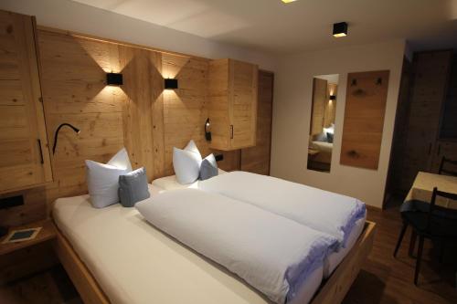 a bedroom with a large bed with white sheets and pillows at Hotel Maroi in Wald am Arlberg