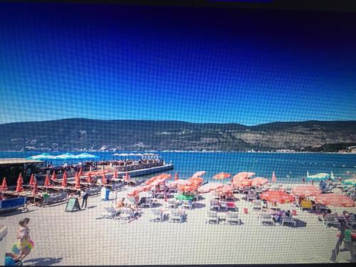 a beach with chairs and umbrellas and the water at Solar Apartments in Herceg-Novi