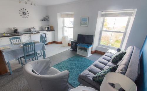 a living room with a couch and chairs and a kitchen at Utopia Apartments in Perranporth
