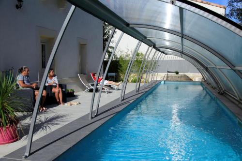 a swimming pool in a house with people sitting next to it at Le Clos du Théron, chambre d'hôte in Cournonterral