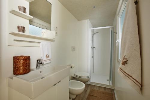 a white bathroom with a sink and a toilet at Dei Fiori Camping Village in Cavallino-Treporti