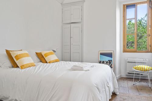 a white bedroom with a large bed and a window at Cargèse, appartement de charme surplombant le port in Cargèse