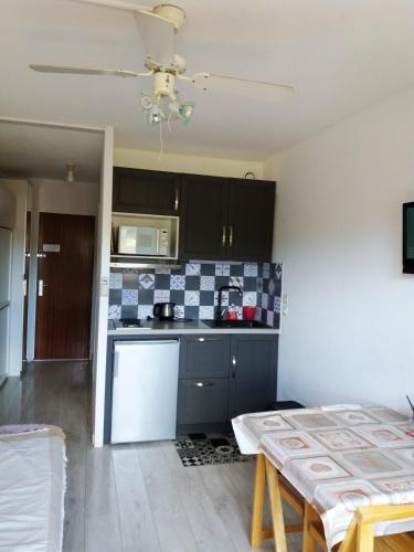 - une cuisine avec des armoires noires et un réfrigérateur blanc dans l'établissement Studio cosy avec vue sur la mer à Bormes-les-Mimosas, 20 m²., à Bormes-les-Mimosas