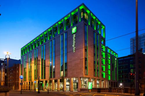 un edificio con luces verdes en el lateral. en Holiday Inn Manchester - City Centre, an IHG Hotel en Mánchester