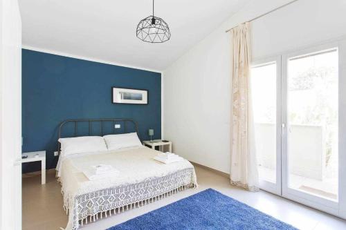 a bedroom with a bed and a blue wall at Alka Loft e Spa in Alcamo
