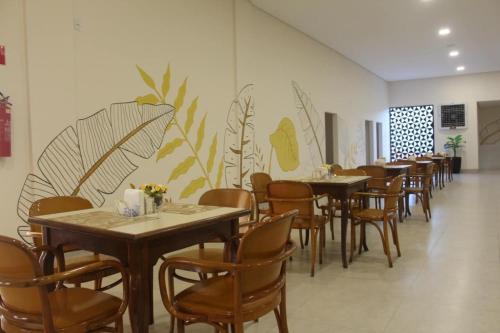 Un comedor con mesas y sillas y una pared con plantas. en Hotel Oscar Gold Janaúba, en Janaúba