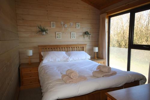 a bedroom with a bed with towels on it at Hartland Hideaway Lodge in Woolfardisworthy