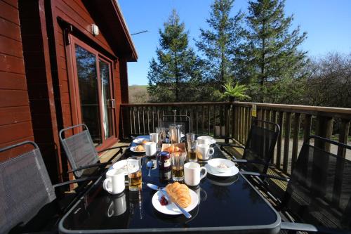 a table with food and drinks on a balcony at Hartland Hideaway Lodge in Woolfardisworthy
