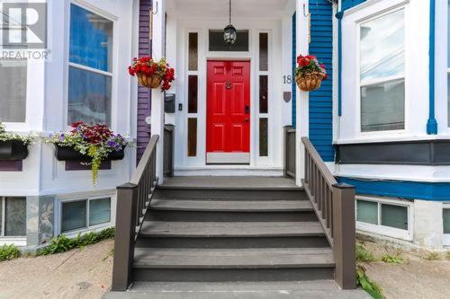 a red door on a blue house with stairs at The Jellybean Heritage Inn in St. John's