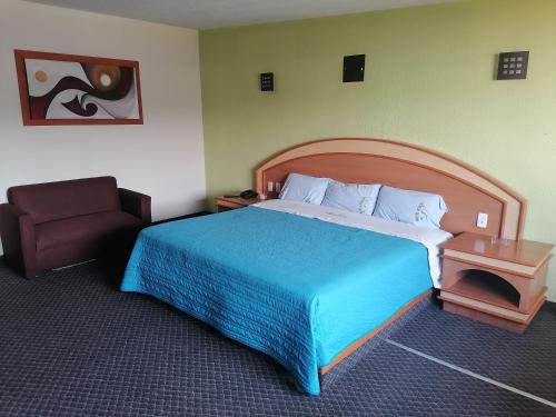 a hotel room with a large bed and a chair at Hotel Puerta del Sol in Toluca