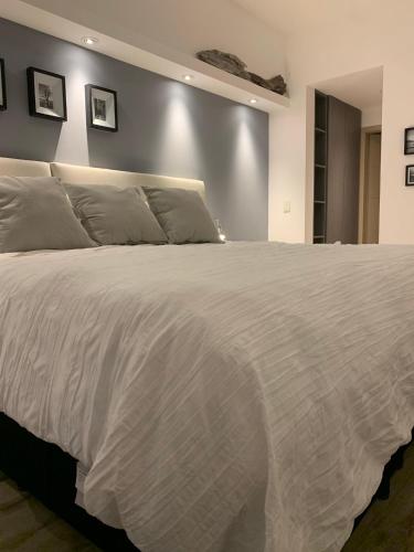 a bedroom with a large bed with white sheets at URBANA SUITES & STUDIOS 440 in San Carlos de Bariloche