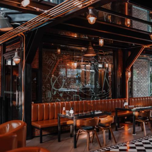 a restaurant with leather chairs and tables and a wall at Letana Hotel in Bang Phli