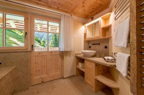ein Badezimmer mit Holzschränken, einem Waschbecken und einem Fenster in der Unterkunft Chalet Berghaus Manuaf in Schruns-Tschagguns