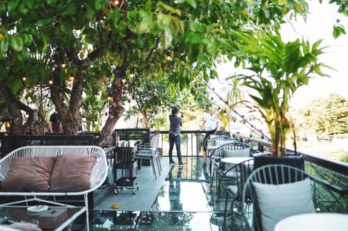 a man standing on a balcony with tables and chairs at Letana Hotel in Bang Phli