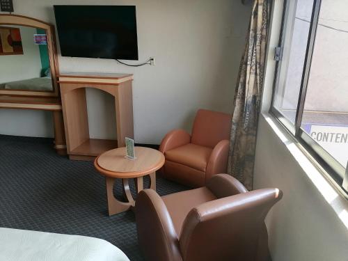 a room with a couch and a chair and a tv at Hotel Puerta del Sol in Toluca