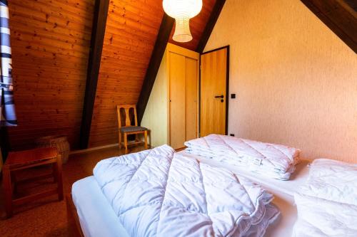 ein Schlafzimmer mit einem weißen Bett in einem Zimmer in der Unterkunft Ferienwohnpark Immenstaad am Bodensee Nurdachhaus Typ 8 NDT 014 in Immenstaad am Bodensee