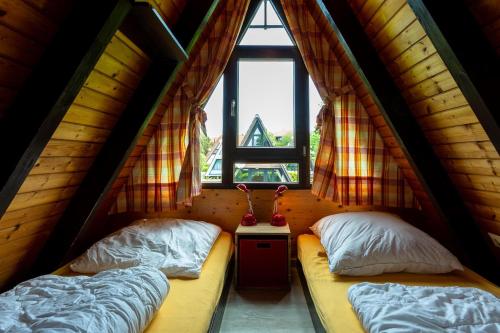 deux lits dans une chambre avec une fenêtre dans l'établissement Ferienwohnpark Immenstaad am Bodensee Nurdachhaus Typ 7 ND 48, à Immenstaad am Bodensee