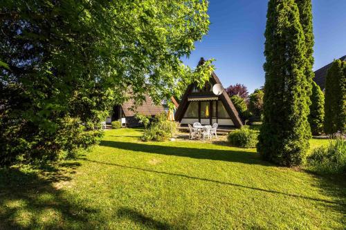 ein Haus mit einem Rasenhof mit einem Zelt in der Unterkunft Ferienwohnpark Immenstaad am Bodensee Nurdachhaus Typ 7 ND 56 in Immenstaad am Bodensee