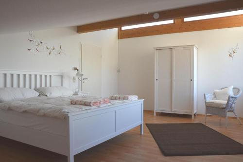 ein Schlafzimmer mit einem weißen Bett und einem Stuhl in der Unterkunft Ferienwohnpark Immenstaad am Bodensee Ferienhaus Normannenweg in Immenstaad am Bodensee