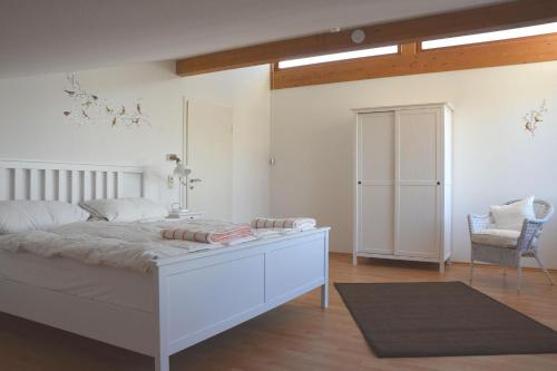une chambre avec un lit blanc et une chaise dans l'établissement Ferienwohnpark Immenstaad am Bodensee Ferienhaus Normannenweg, à Immenstaad am Bodensee