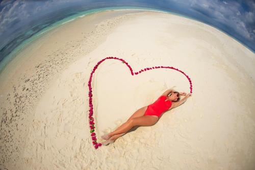 a woman laying on a beach with a heart at PERLA Dhangethi in Dhangethi