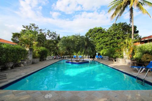 una piscina con agua azul y palmeras en Villa del Sueño en Playa Hermosa