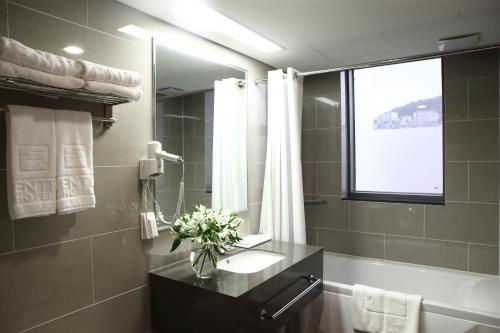 a bathroom with a sink and a vase of flowers at Aventree Hotel Busan in Busan