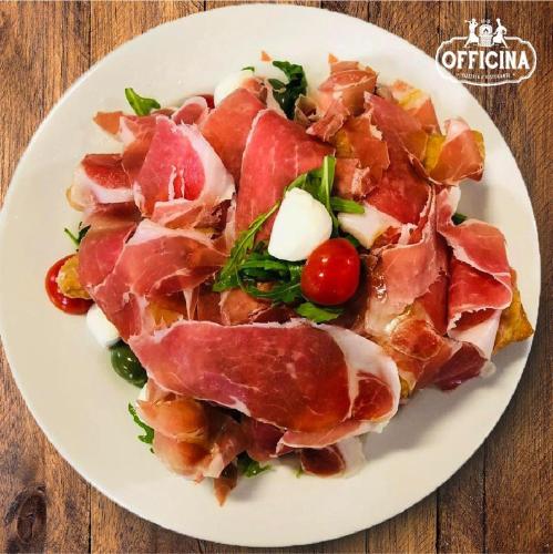a white plate with ham and vegetables on a table at Hotel Panorama in Cambiano