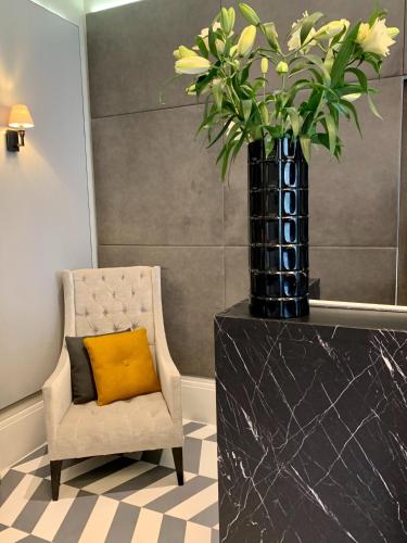 a chair with a yellow pillow and a vase with flowers at Eccleston Square Hotel in London