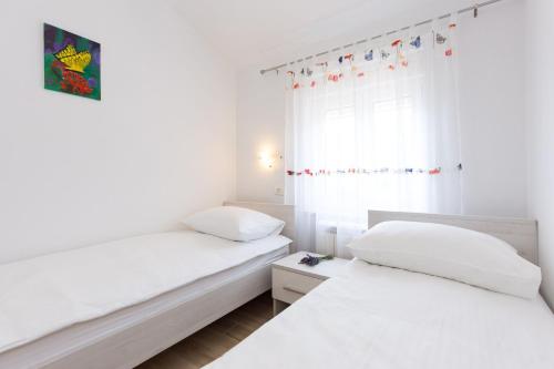 two beds in a room with white walls and a window at Villa Lavandula in Tribalj