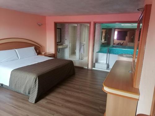 a bedroom with a bed and a bathroom with a tub at Hotel Puerta del Sol in Toluca