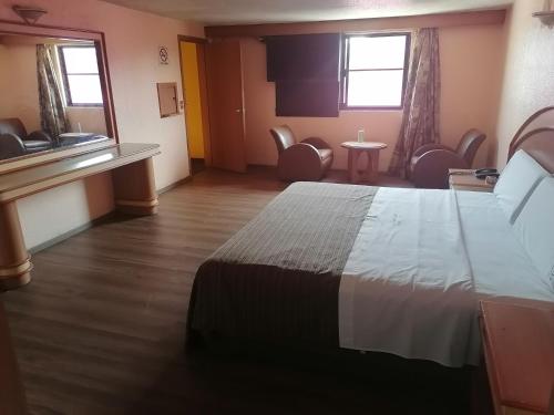 a hotel room with a large bed and chairs at Hotel Puerta del Sol in Toluca