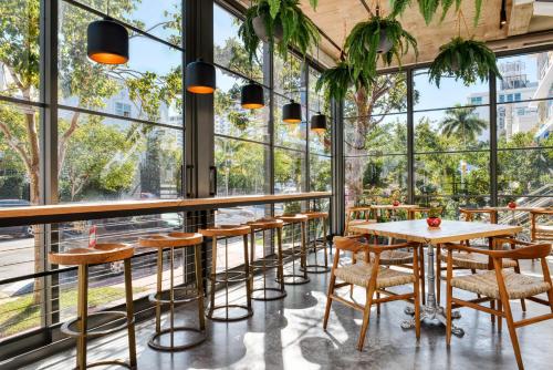 un restaurante con mesas, sillas y ventanas grandes en Kaskades Hotel South Beach, en Miami Beach