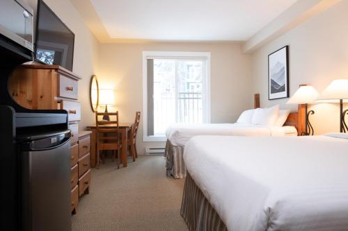 a hotel room with two beds and a desk at The Vance Creek Hotel & Conference Centre in Silver Star