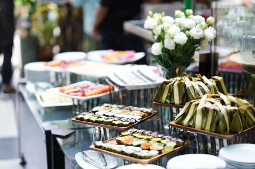 a buffet line with trays of sushi and vegetables at Letana Hotel in Bang Phli